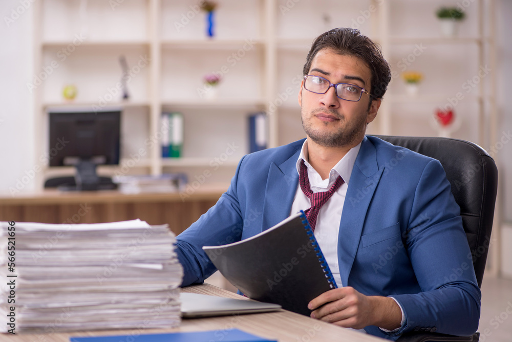 Young male employee and too much work in the office Young male employee and too much work in the office