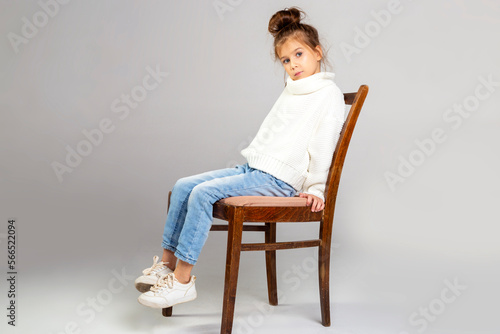 little girl sitting on a chair wearing jeans pants