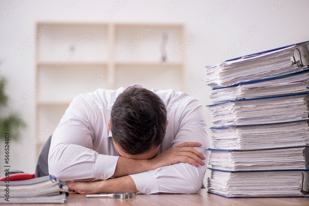 Young male employee and too much work in the office Young male employee and too much work in the office