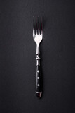 Metal kitchen fork on a dark textured concrete background