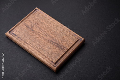 Empty wooden cutting board on dark textured concrete background