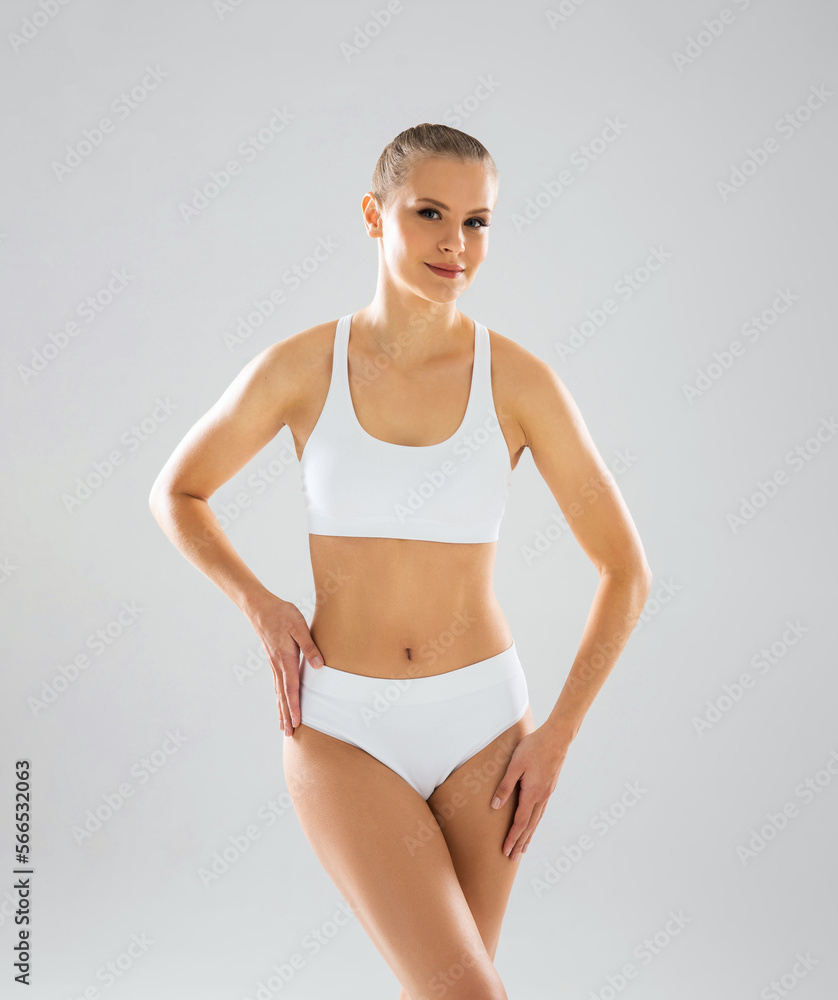 Young, fit and beautiful blond woman in white swimsuit isolated on grey background. Healthcare, diet, sport and fitness concept. Young, fit and beautiful blond woman in white swimsuit isolated on grey background. Healthcare, diet, sport and fitness concept.