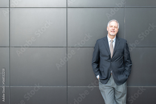 Senior business man standing next to a black wall © Minerva Studio