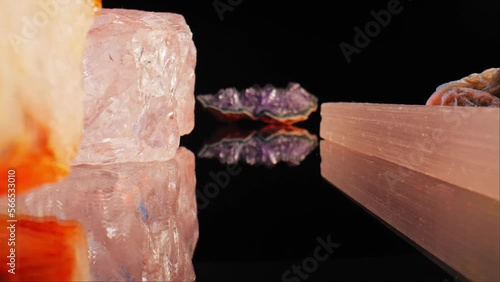 Zoom shot between crystals, minerals and precious stones, reflection under them. Abstract shot black background. photo