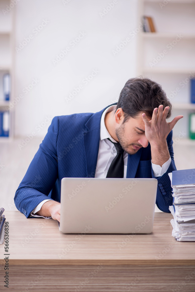 Young male employee and too much work in the office Young male employee and too much work in the office