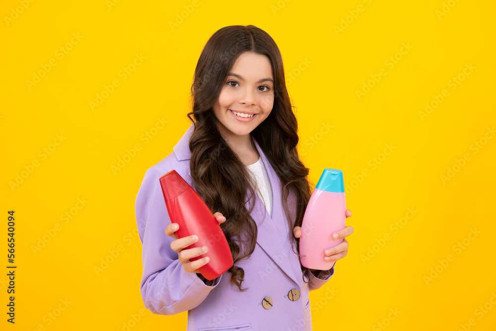 Teen child girl with shampoo bottle or shower gel isolated on yellow background. Kids hair cosmetic product. Happy teenager, positive and smiling emotions of teen girl. Teen child girl with shampoo bottle or shower gel isolated on yellow background. Kids hair cosmetic product. Happy teenager, positive and smiling emotions of teen girl.