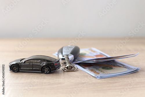 Black car, key and us dollar on wooden table. Finance and insurance concept. 