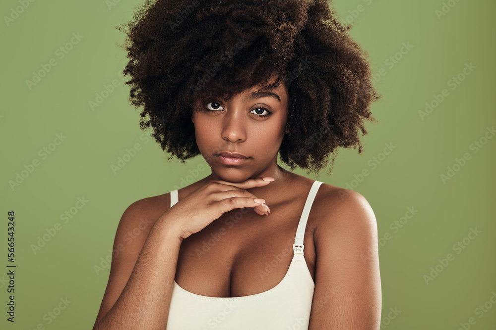 Confident young black female model touching chin in green studio Confident young black female model touching chin in green studio