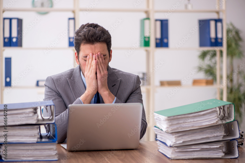 Young male employee and too much work in the office Young male employee and too much work in the office