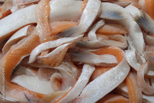 Pieces of salted salmon belly. Seafood. Fresh raw fish as background. View from above.