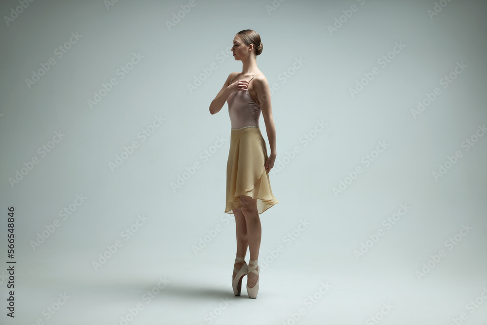 Young ballerina practicing dance moves on light grey background Young ballerina practicing dance moves on light grey background