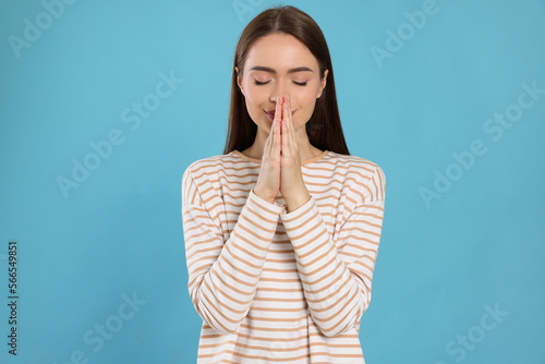 Foto Woman with clasped hands praying on turquoise background