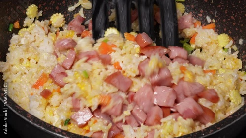 Chef frying rice with corn and bacon in pan close-up. Woman chief cooking dish with grilled vegetables, meat, Ingredients for fried rice recipe . Food and cook concept.	
