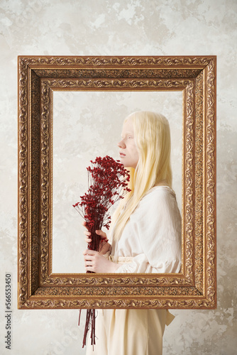 Cuadro en lienzo Young pretty albino woman with bunch of dried flowers standing behind large pict