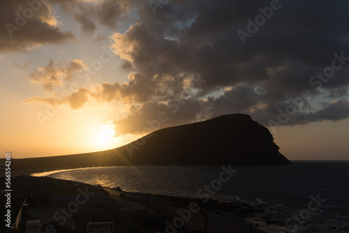 Sunset on the beach, golden sunbeams breaking through the gray storm clouds, with Red Mountain and ocen in the background. La Tejita, Tenerife, Canary Islands. Spain photo