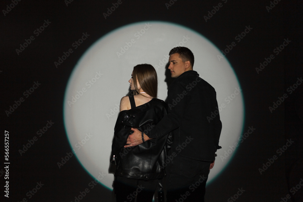Beautiful fashion couple hipster woman and man in trendy denim clothes on black background with light circle