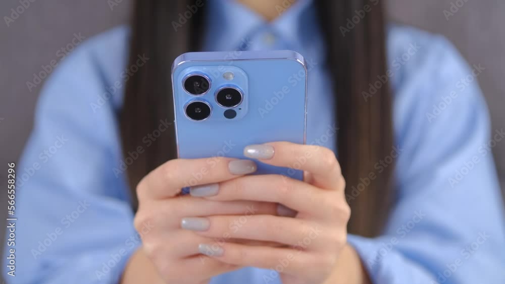Girl typing a message on a smart phone. Unrecognizable female person texting online with blue mobile phone. Young woman writing a comment on a social media app with new cellphone Girl typing a message on a smart phone. Unrecognizable female person texting online with blue mobile phone. Young woman writing a comment on a social media app with new cellphone