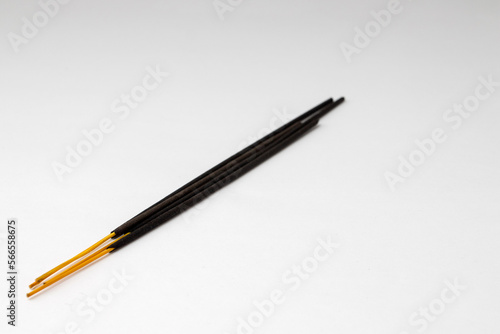 Black aromatic incense sticks on a white background