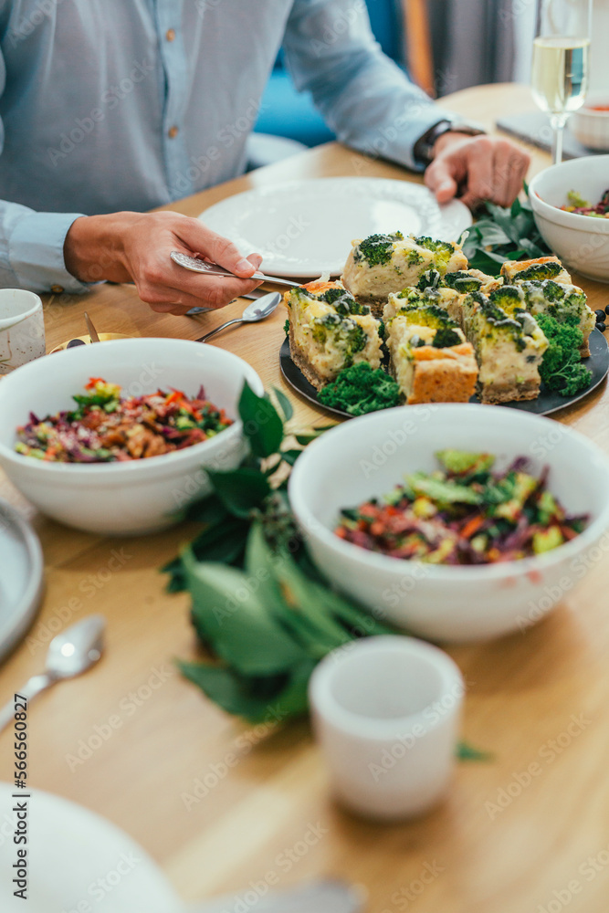 Midsection of man taking broccoli casserole while sitting at dining table Midsection of man taking broccoli casserole while sitting at dining table