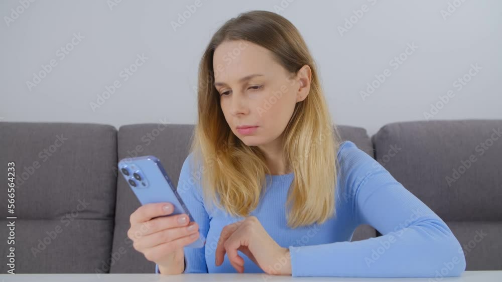 Adult blonde woman using modern smart phone in the living room at home Adult blonde woman using modern smart phone in the living room at home