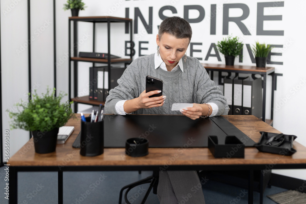 Business woman dialing a number on the phone with a business card in her hands Business woman dialing a number on the phone with a business card in her hands
