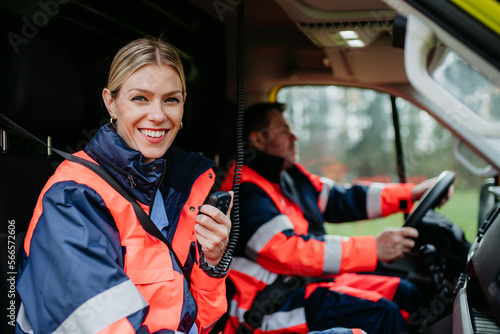 Portrait of young woman doctor sitting and talking in to walkie-talkie in ambulance car.