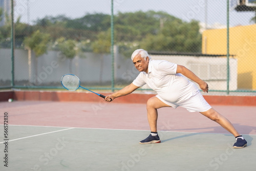 Senior man playing badminton outdoor at badminton court. Concept of active lifestyle being on pension © G-images