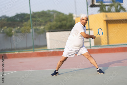Senior man playing badminton outdoor at badminton court. Concept of active lifestyle being on pension © G-images