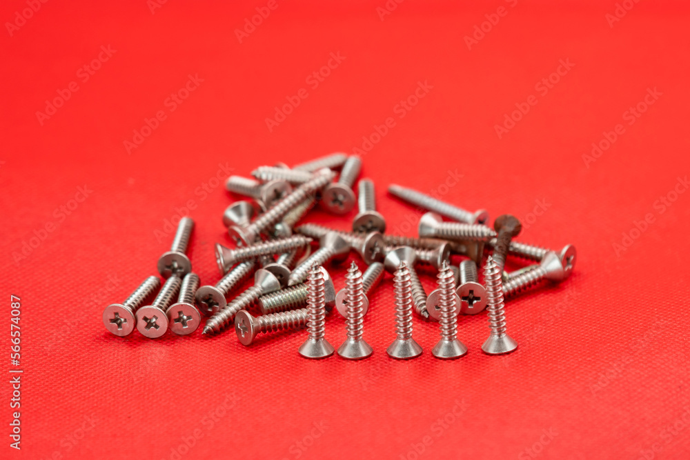 Tapping screws made of steel on red color background, metal screw, iron screw, chrome screw, screws as a background, wood screw, concept industry. copy space for text. Tapping screws made of steel on red color background, metal screw, iron screw, chrome screw, screws as a background, wood screw, concept industry. copy space for text.