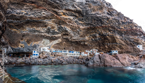 Small fishing village under the huge rocks, rough coastline