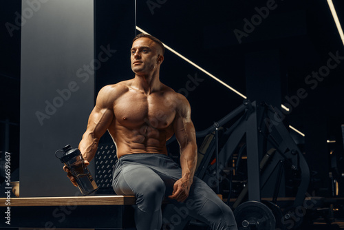 Fotografie Bodybuilder preparing to do exercises with dumbbells in gym