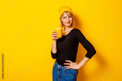 Woman drinking tea on yellow background