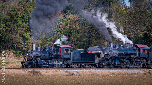 A View of Two Steam Engines, blowing Smoke and Steam One Pulling Ahead of the Other on a Sunny Day