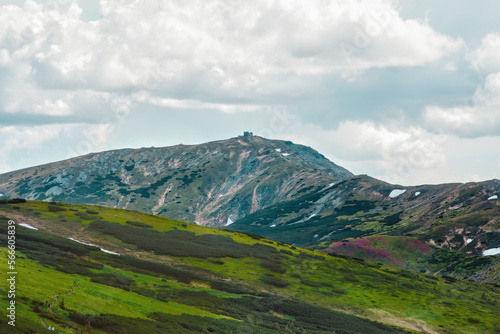 View of Carpathian mountains in summer, meadows, rocks, sky and clouds, flowers and snow, abandoned observatory at the top Pip Ivan, amazing landscape and background, part of hiking and trekking trail