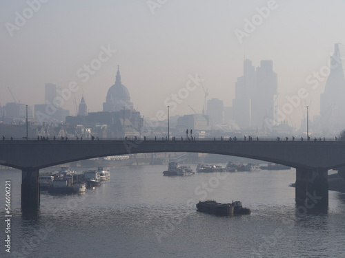 Commuters struggle into work over Waterloo Bridge, on a cold, foggy, misty morning. City of London can be seen in the background, River Thames in foreground.