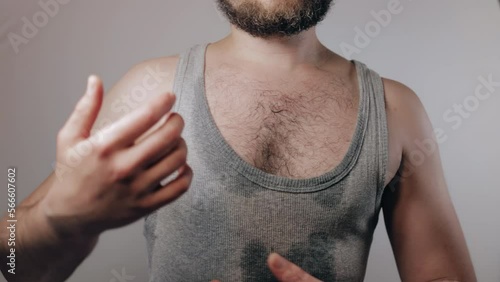 Close up slow motion shoot of man in shirt soaked with sweat fans himself with hands because of heat wave and touching his hairy armpit. Removal of unwanted hair, using of deodorant or antiperspirant
