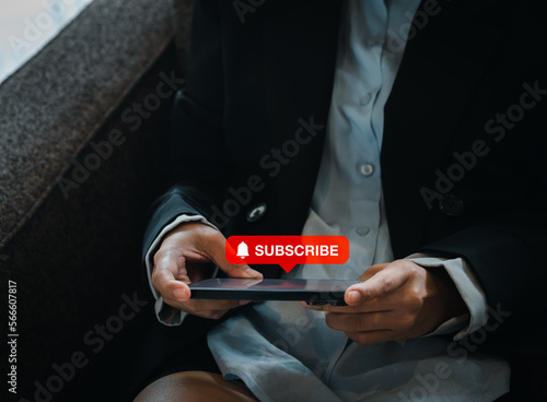 Subscription concept. Big red subscribe button with bell icon appear on smart mobile phone in hand. Smartphone horizontal style holding by businesswoman who watching on entertainment applicatiion.