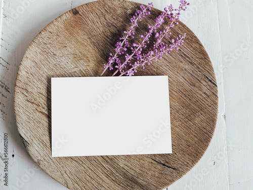 White, blank paper card invitation on a wooden plate with purple flowers mock-up