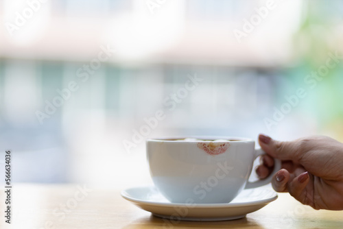 Coffee cup with lipstick stain. Woman holding coffee mug drinking coffee in the morning.