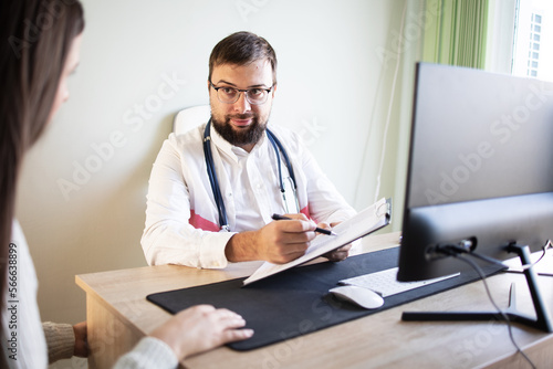 Patient no face at the doctors office. Male doctor with a beard and glasses with a stethoscope listens carefully to the patient in the office. Concept: health, patient. doctor, insurance policy