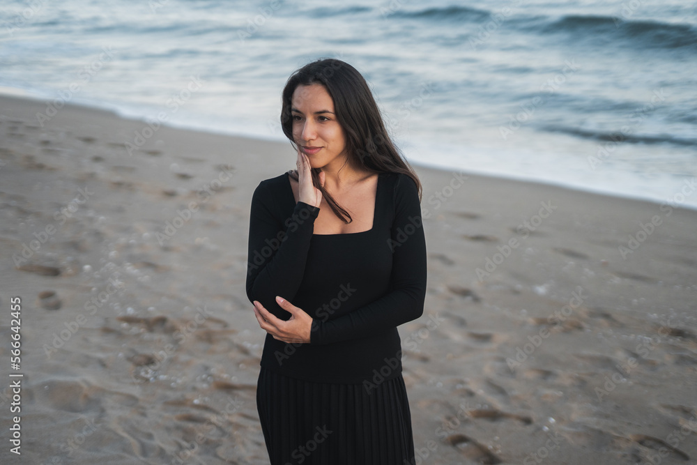 Delighted young ethnic female tourist standing on beach and smiling Delighted young ethnic female tourist standing on beach and smiling