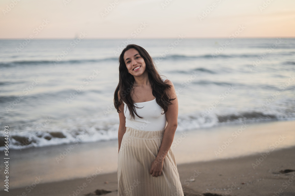 Cheerful young ethnic woman walking on sandy seashore during summer vacation Cheerful young ethnic woman walking on sandy seashore during summer vacation