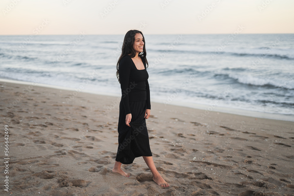 Self assured ethnic lady shaking hair on sandy seashore and smiling Self assured ethnic lady shaking hair on sandy seashore and smiling