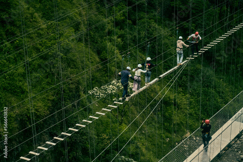 Personas en deportes extremos cruzando un puente sobre un río.