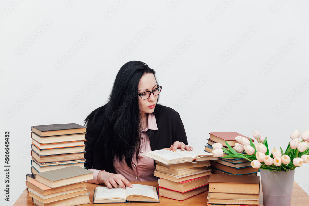 a woman reading a book in a library near a stack of books a woman reading a book in a library near a stack of books