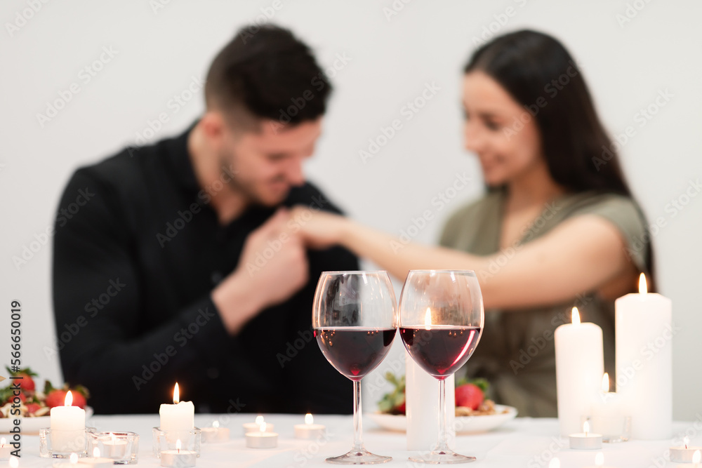 Two glasses with red wine over man kissing woman hand Two glasses with red wine over man kissing woman hand