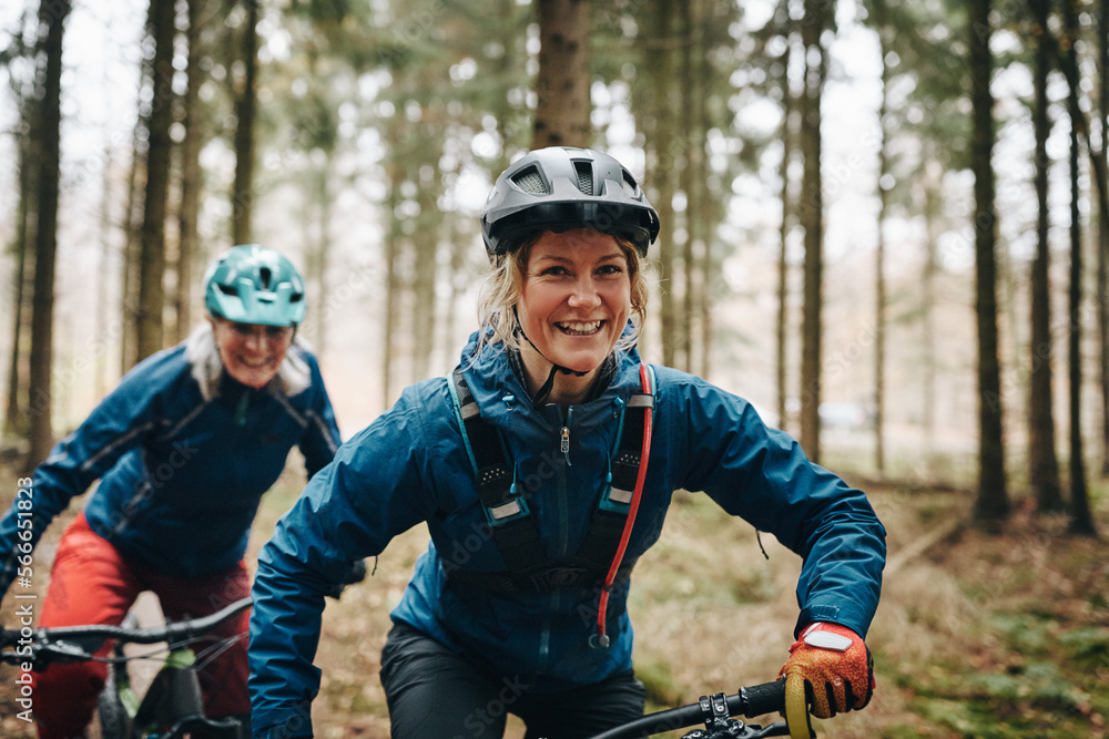Smiling woman mountain biking with her mom in a forest Smiling woman mountain biking with her mom in a forest