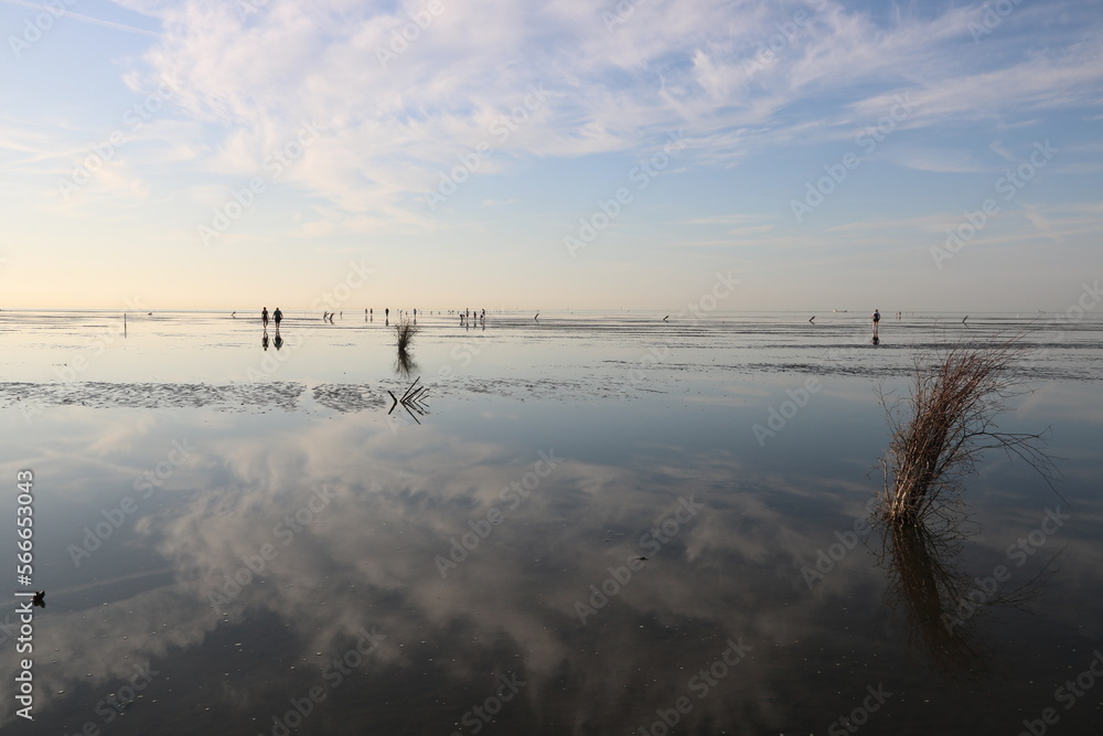 Blick auf das Wattenmeer der Nordsee mit Wattwanderern am Abend Blick auf das Wattenmeer der Nordsee mit Wattwanderern am Abend