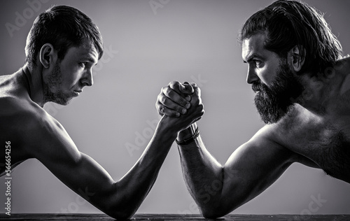 Фотография Arms wrestling thin hand, big strong arm in studio