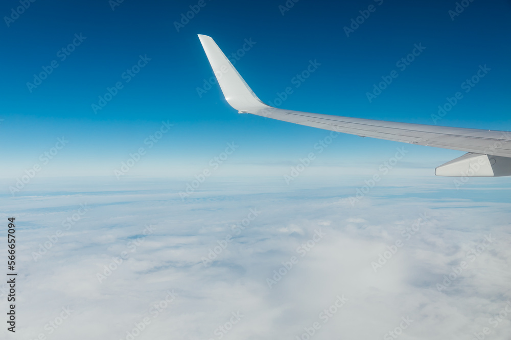 wing of an airplane in the sky with clouds flying over the ground wing of an airplane in the sky with clouds flying over the ground